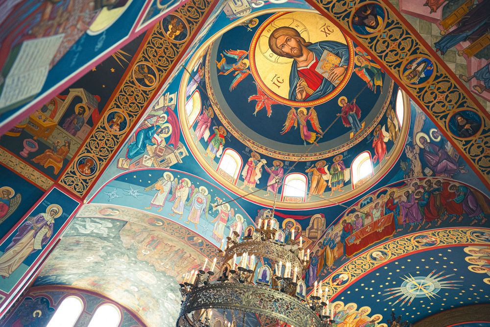 Ornate Orthodox church ceiling with vibrant religious frescoes and intricate Byzantine artwork.