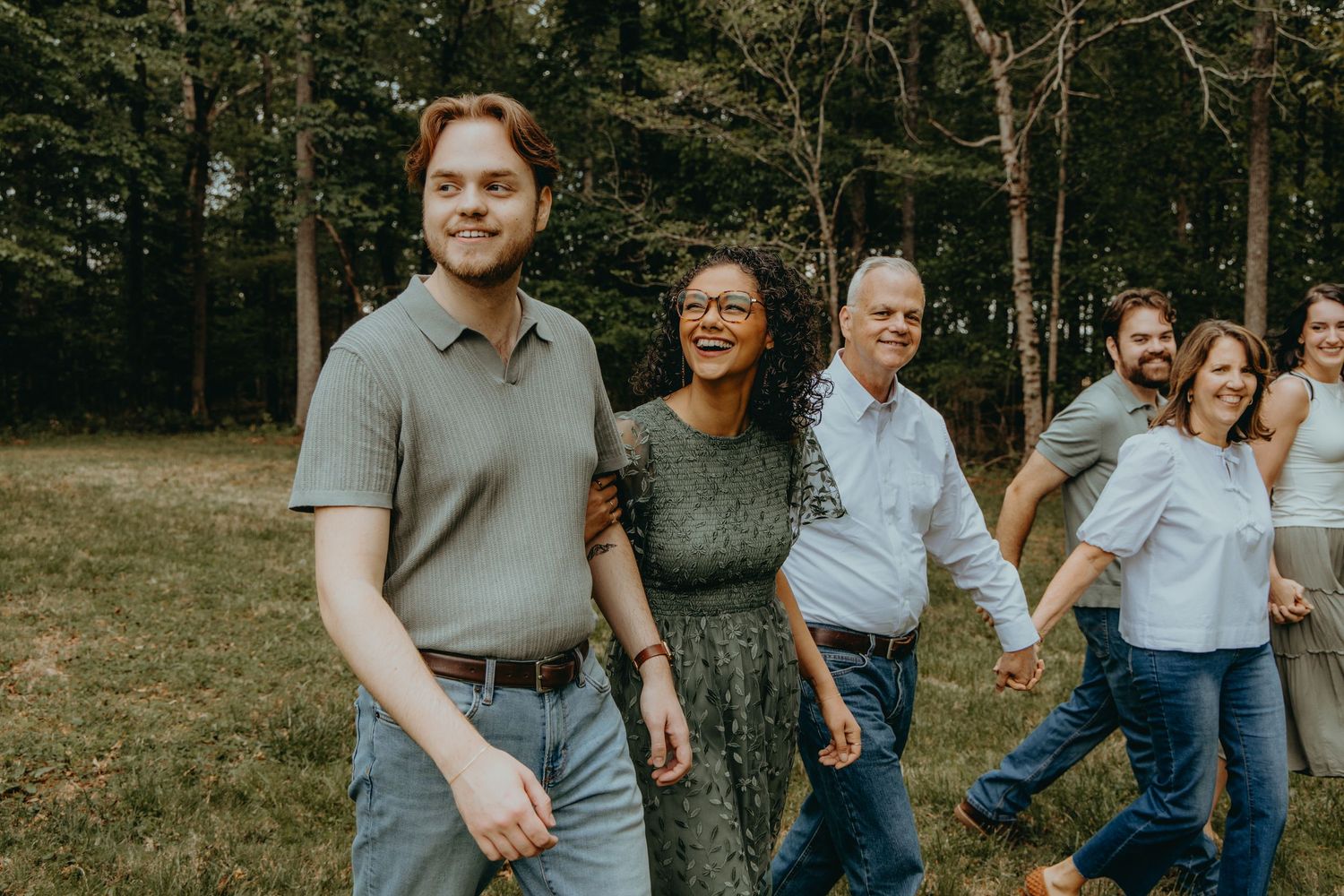 Happy family group walking outdoors in a lush green park, smiling and enjoying time together.