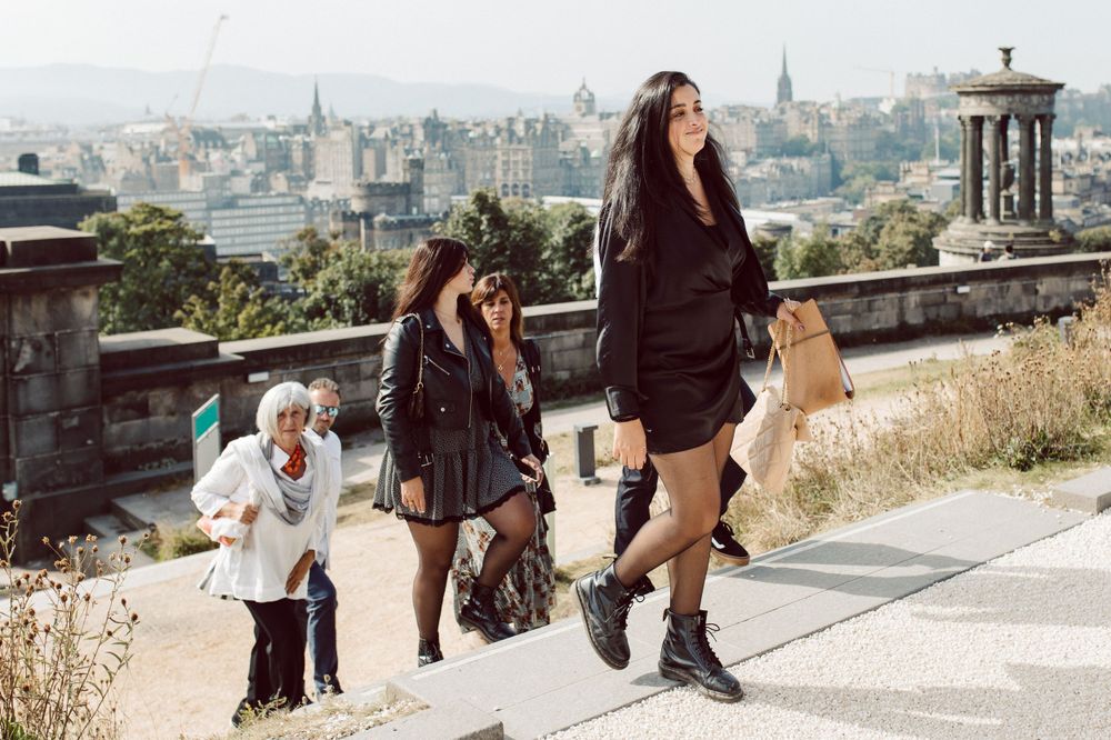 People walking along a paved path with scenic city views in the background.