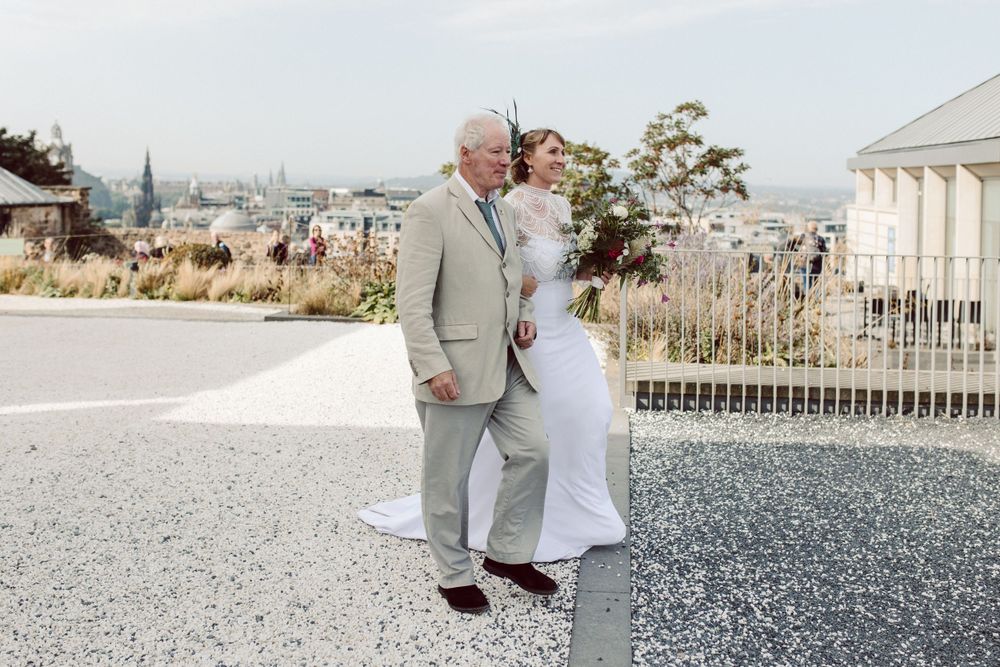 Wedding celebration taking place on a rooftop terrace overlooking a cityscape.