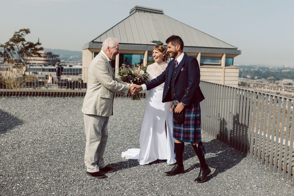 Wedding party interacting on a rooftop venue with urban views.