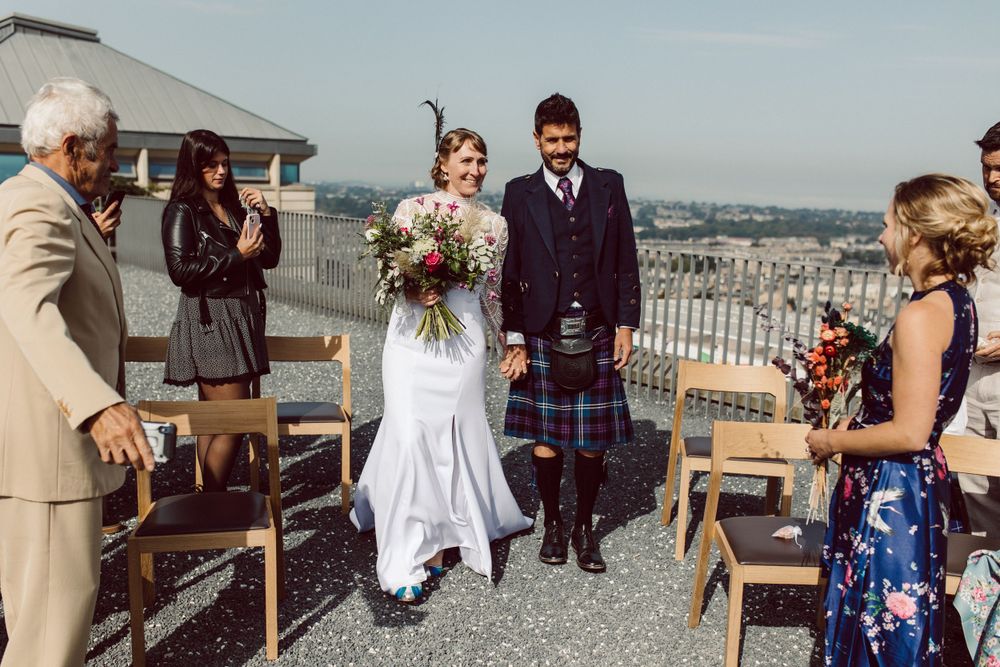 Wedding ceremony setup on a rooftop with chairs and city views.