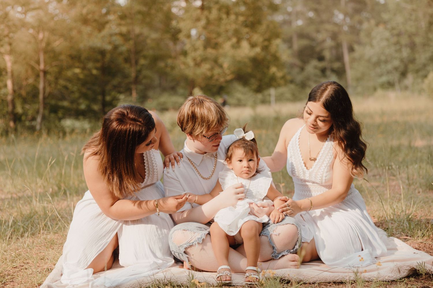 A casual outdoor family photo session shows tender moments on a blanket in a field.