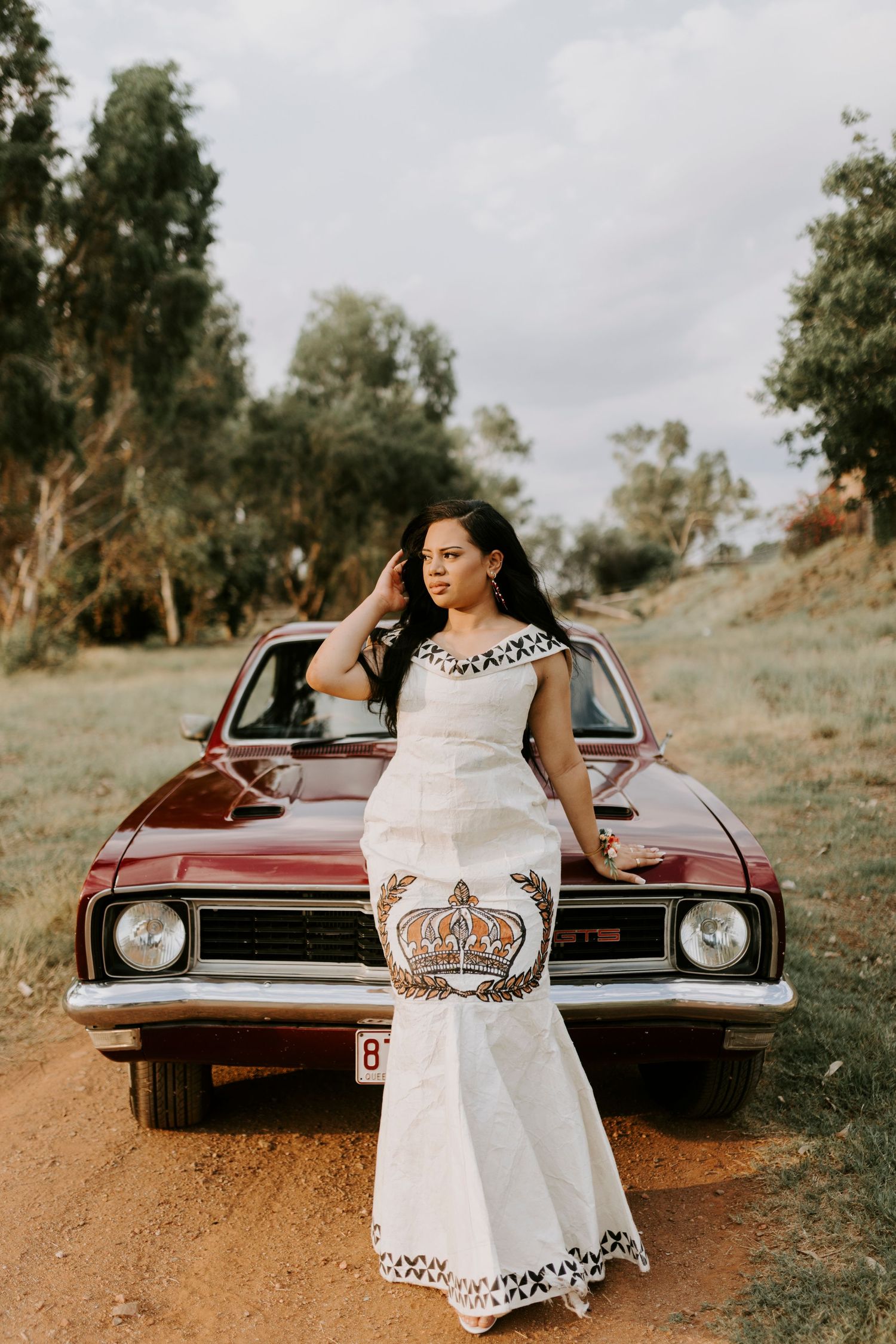 Woman leaning against the car at sunset