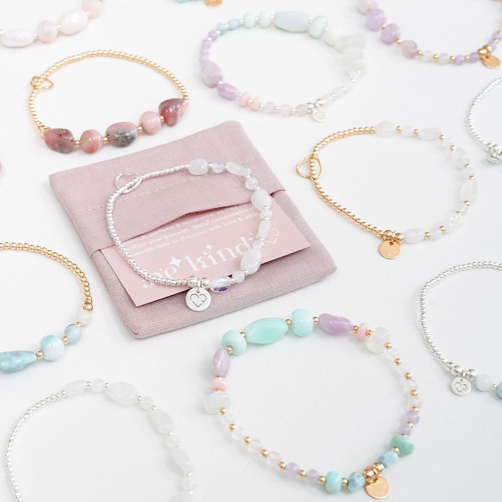 Collection of pastel beaded bracelets with gold accents arranged with pink jewelry pouch.