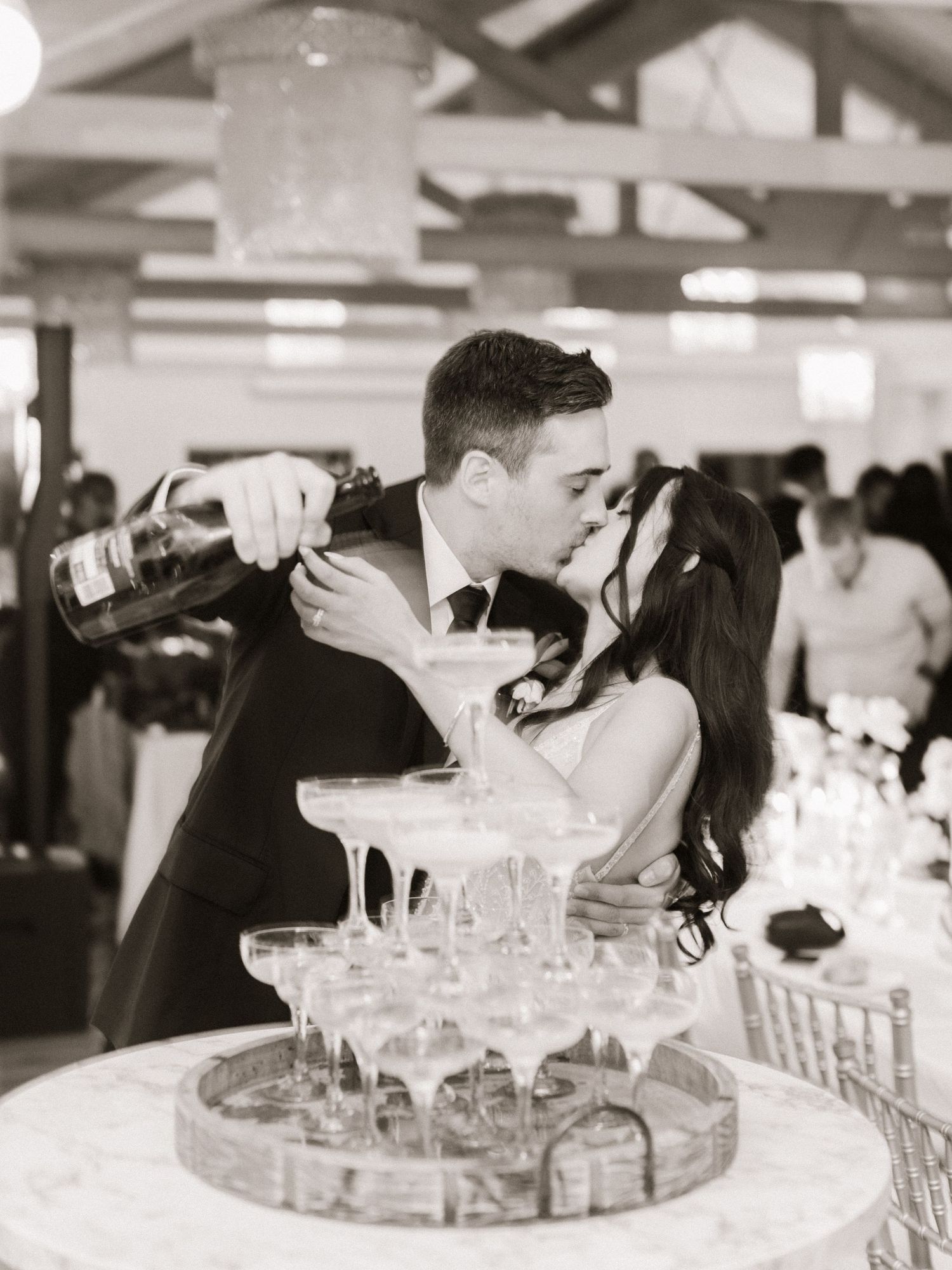 A black and white photo showing a champagne tower being poured at an elegant event.