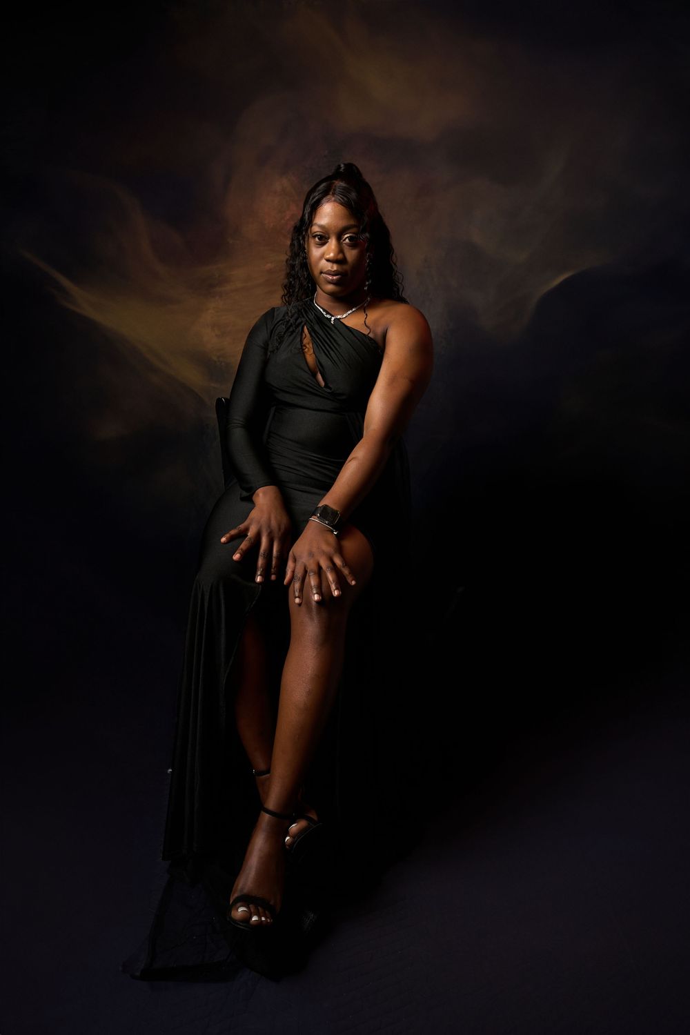 Dramatic low-light maternity poses showcasing pregnancy silhouette in elegant black attire.