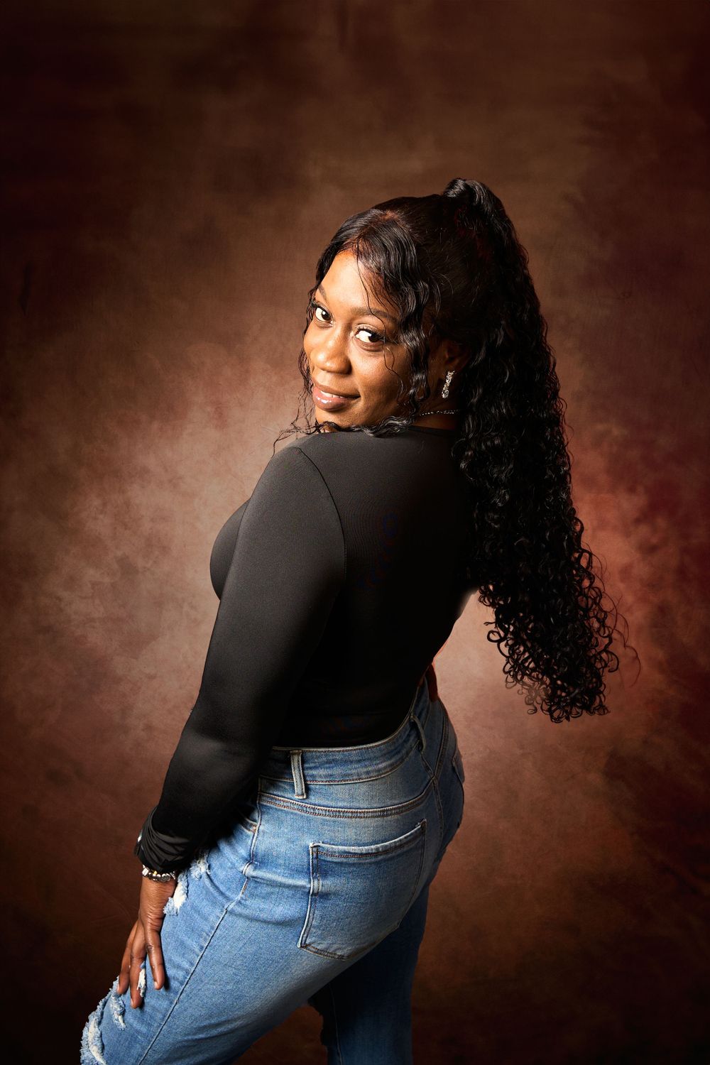 Over-the-shoulder maternity poses in casual denim and black top with natural curls.