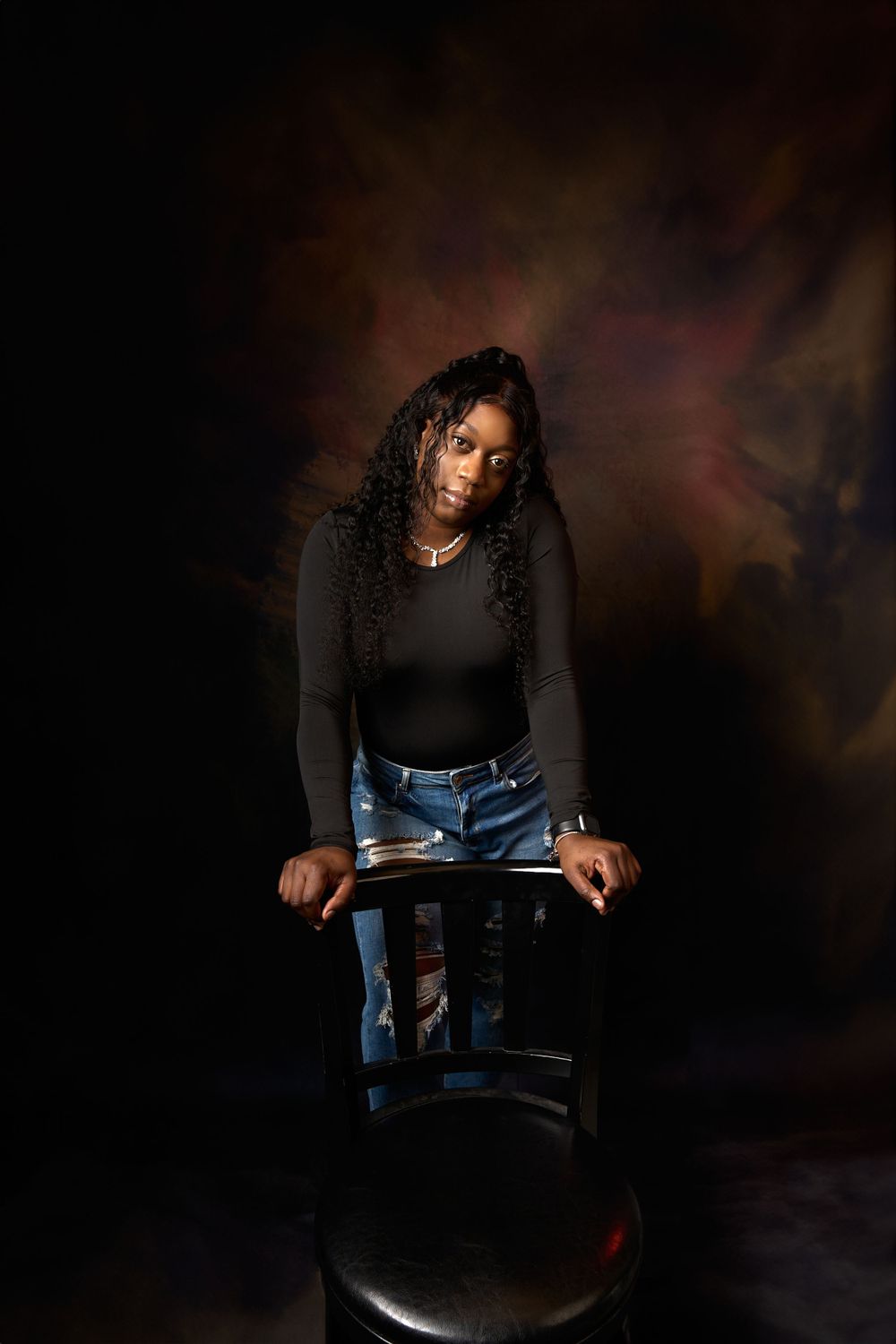 Creative maternity session with dramatic lighting and casual styling in denim and black.
