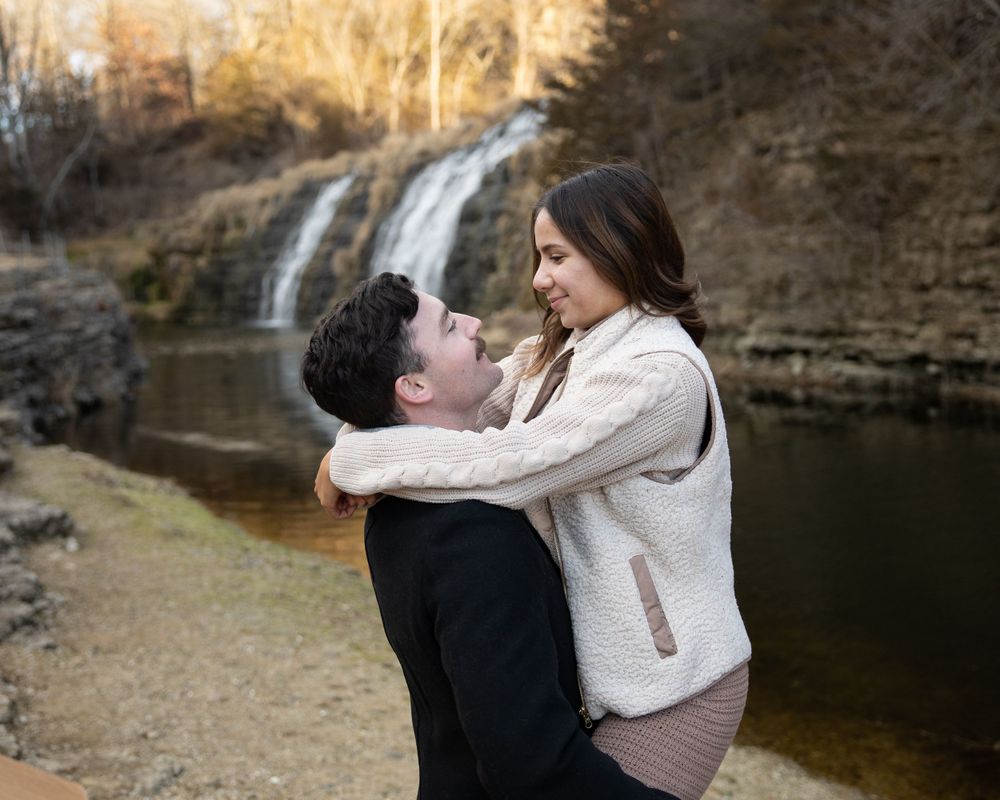 An intimate moment shared between a couple by a scenic waterfall.