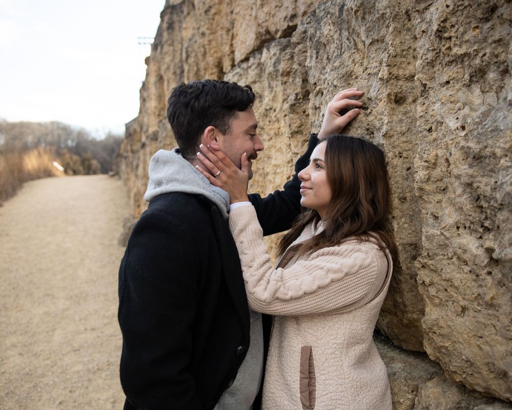A romantic candid moment captured against a rocky cliff backdrop.