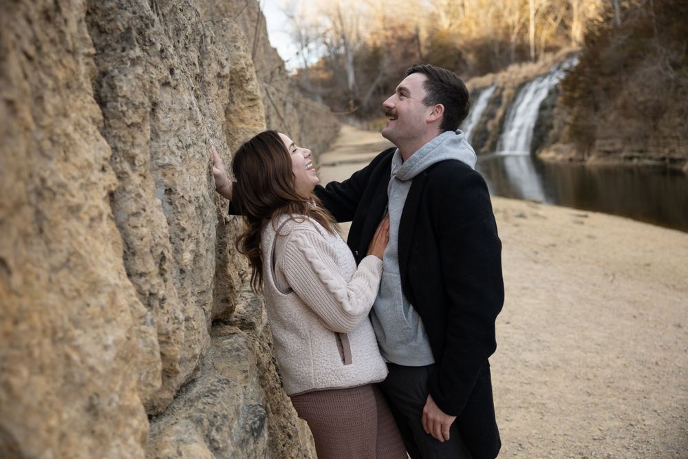 A joyful moment shared between a couple with a waterfall in the background.