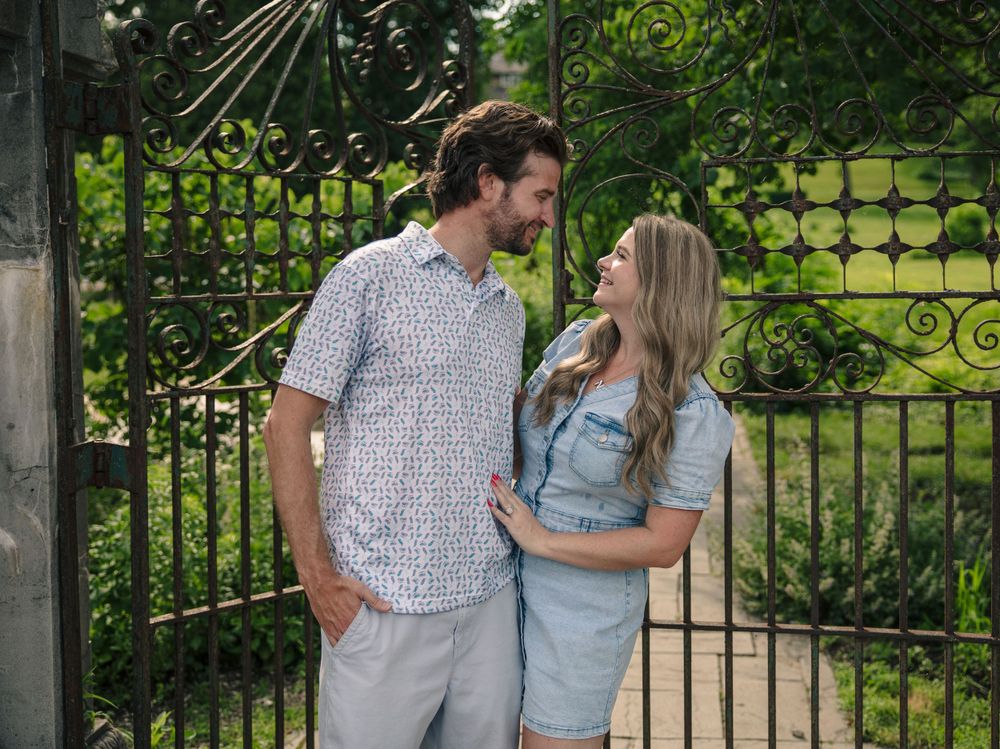 A romantic couple sharing an intimate moment by a wrought iron garden gate.