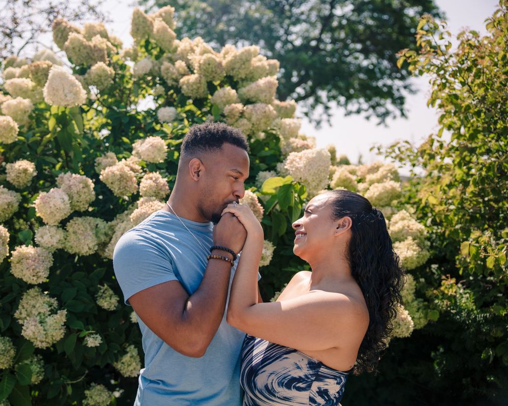 Romantic moment between a couple near blooming white hydrangea bushes on a sunny day.