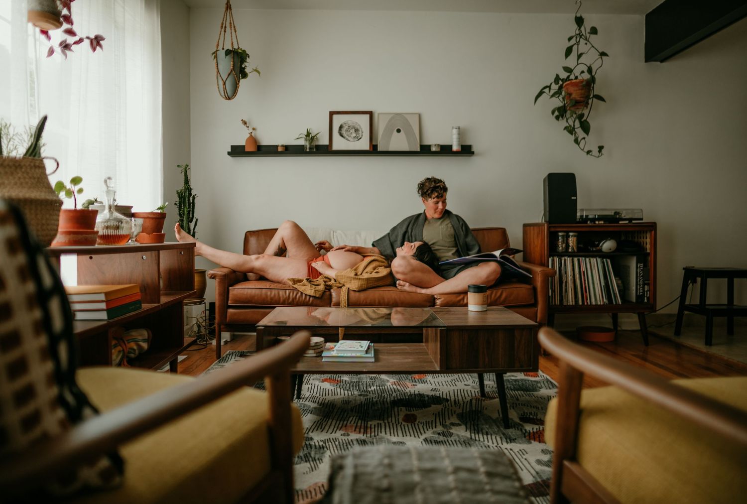 wide shot of couple reading while relaxing on couch portland oregon maternity rushes & waves