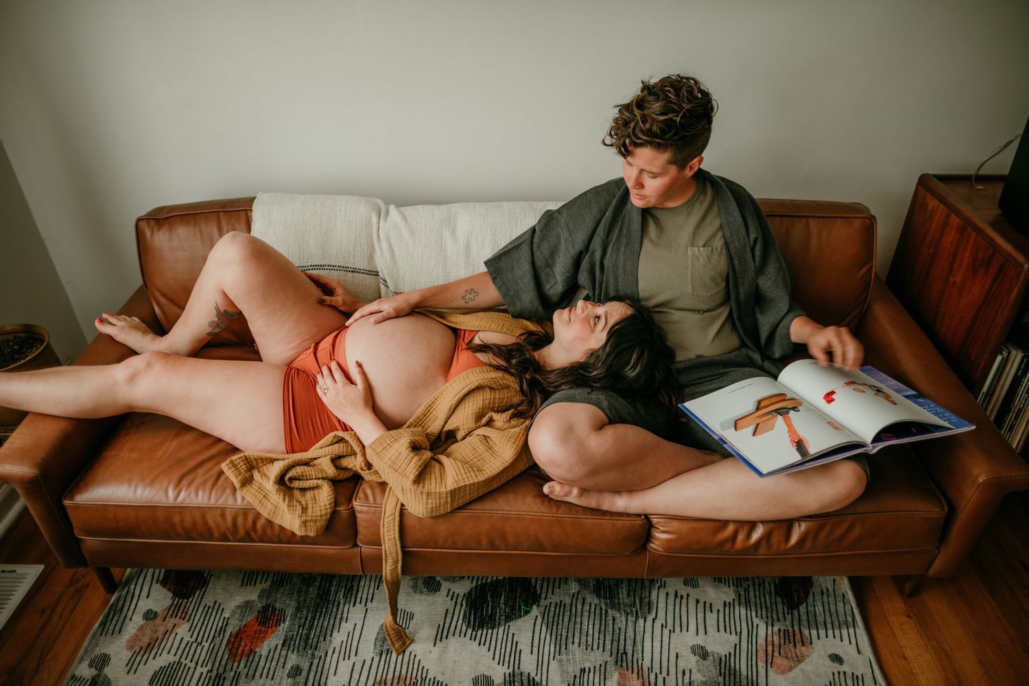 pregnant person looks up at partner adoringly while they read a book portland oregon rushes & waves