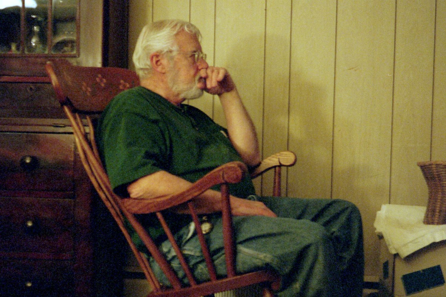 old man in rocking chair, hand to face as if deep in thought