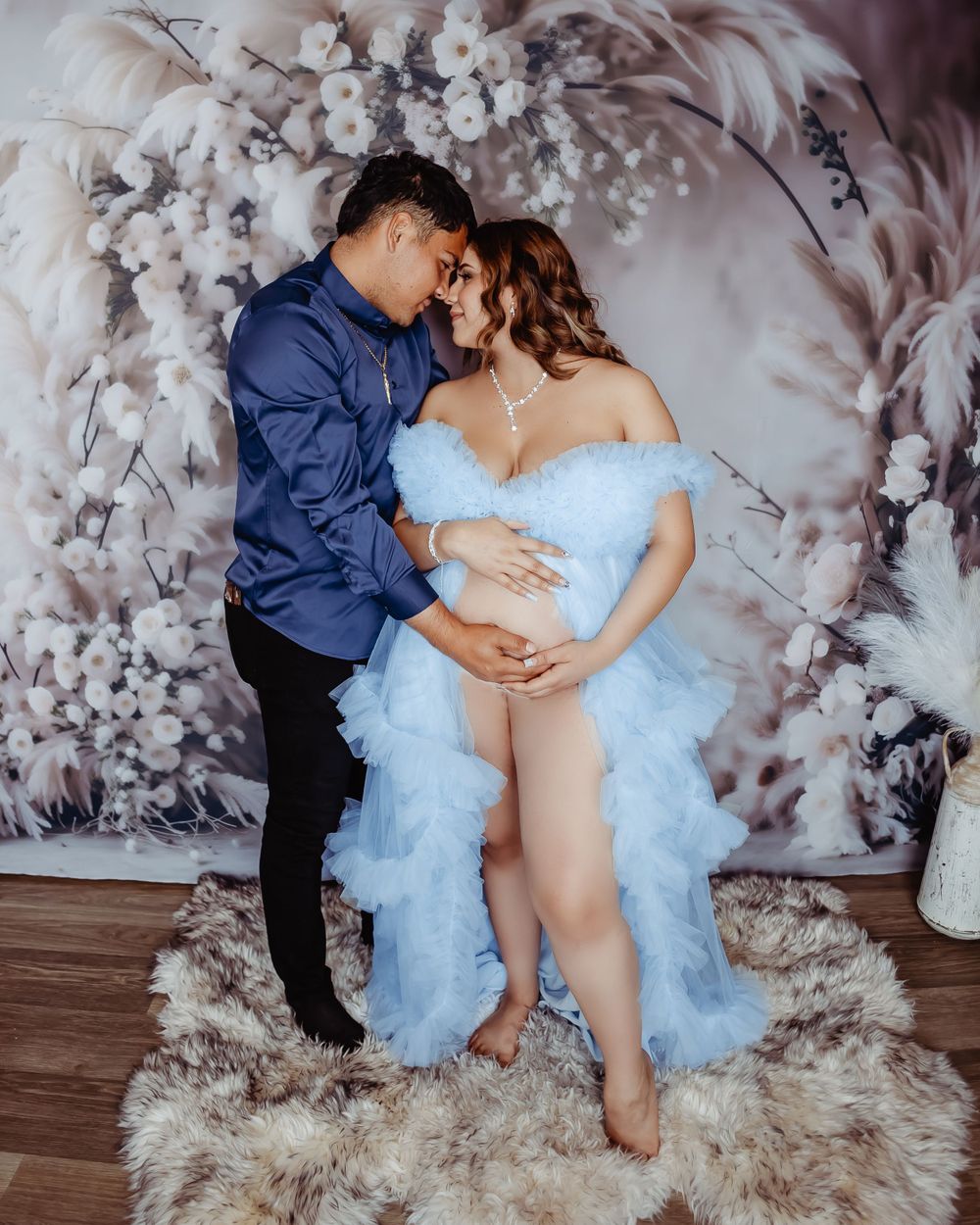 Couple embracing in maternity photoshoot with blue dress.