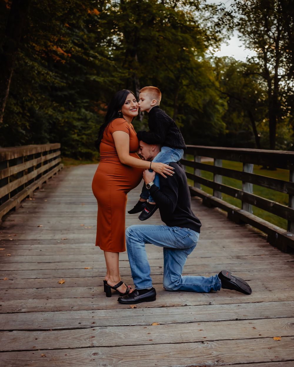 Sweet moment captured on wooden bridge during pregnancy photoshoot.