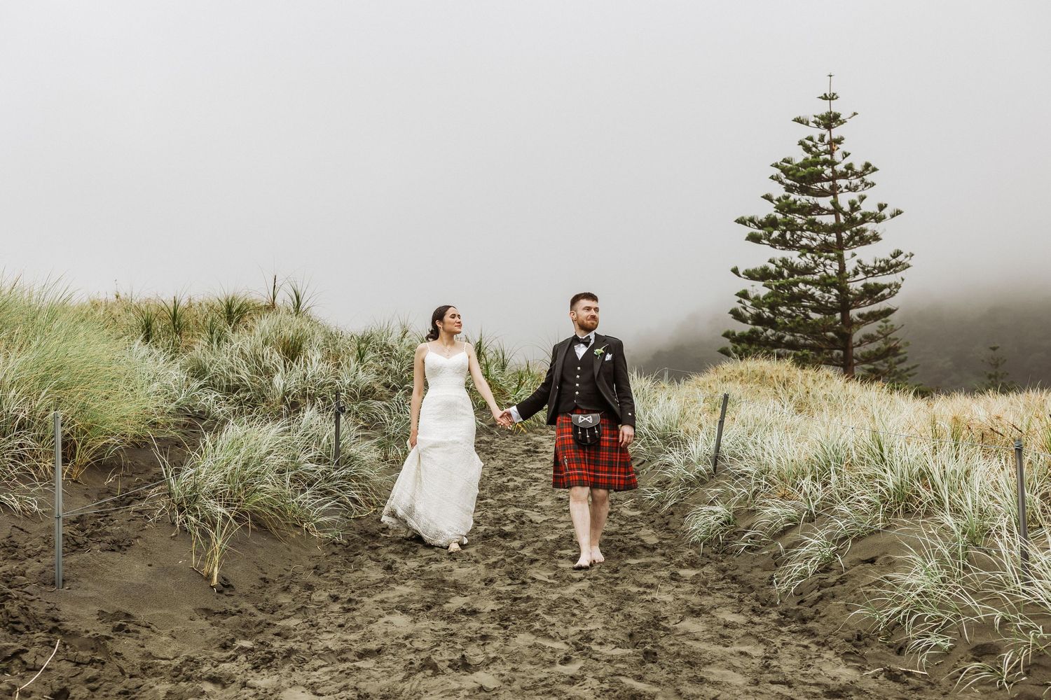 Irish and Malaysian couple at Muriwai beach walking while it is raining. Auckland Photographer