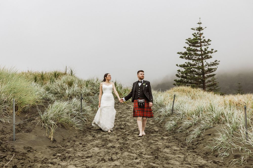 Irish and Malaysian couple at Muriwai beach walking while it is raining. Auckland Photographer