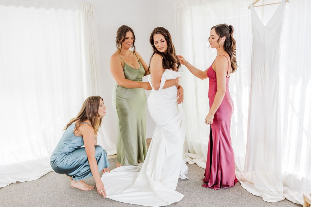 Bride with her bride's maids helping her dress