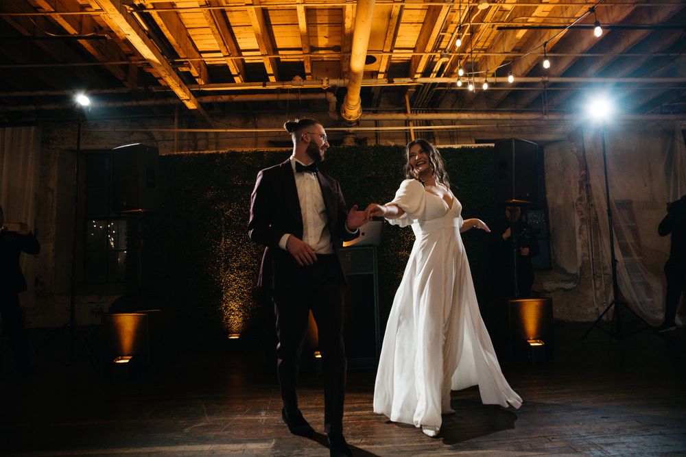 A couple dancing in formal attire under warm industrial lighting.
