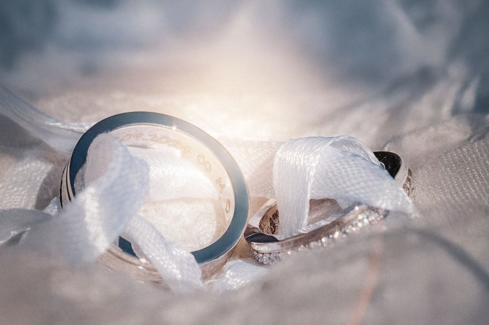 Wedding rings with delicate lace detail in soft dreamy lighting.