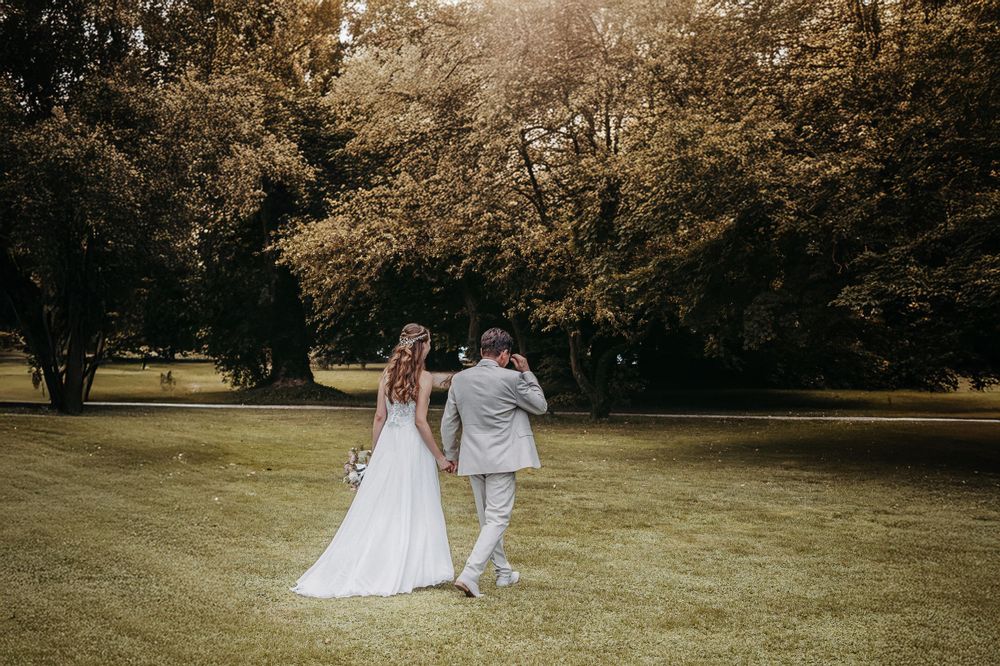 Newlyweds walking together on green lawn during outdoor celebration.