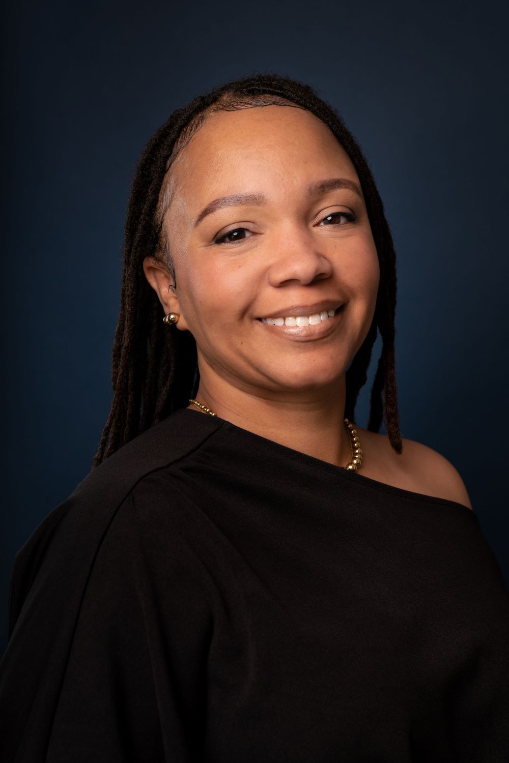 Studio headshot series showing person with dreadlocks and gold necklace.