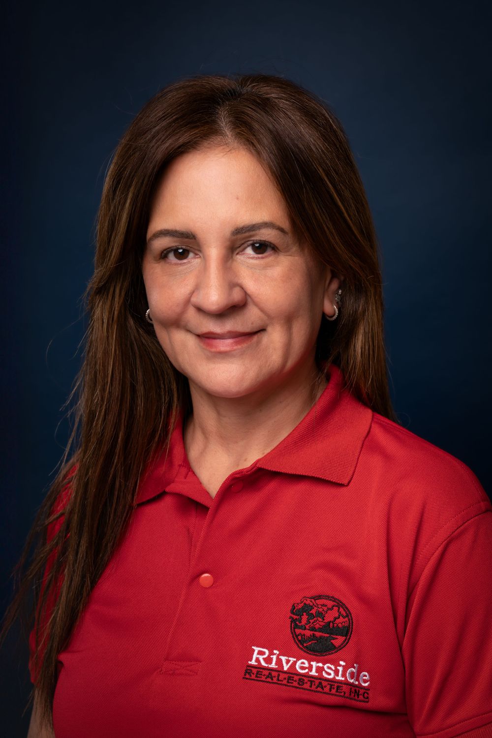 Professional headshot of person in red Riverside polo shirt against dark background.