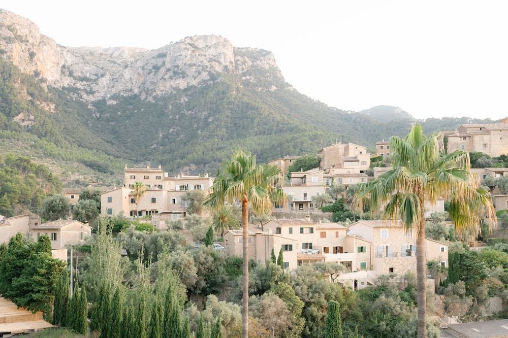 Mediterranean village nestled in mountains with palm trees and stone houses in Mallorca, Spain.