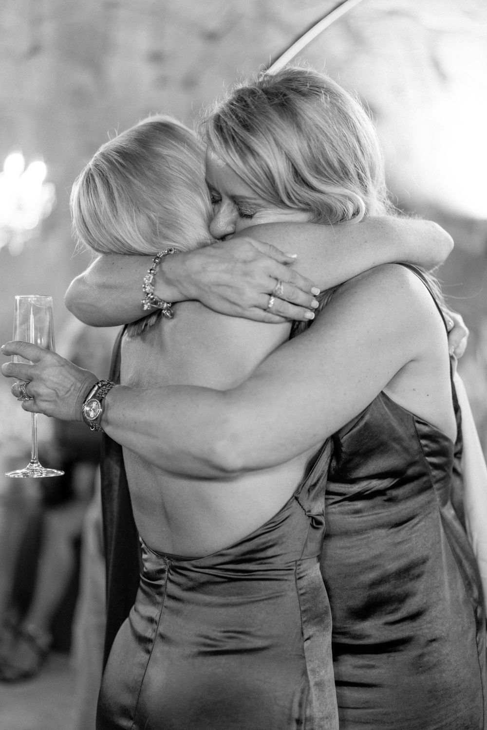 Emotional black and white capture of two people sharing a heartfelt embrace at a wedding celebration.