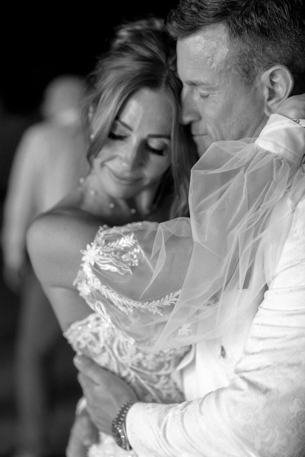 Black and white intimate portrait of newlyweds sharing a tender moment during their first dance at a wedding reception.