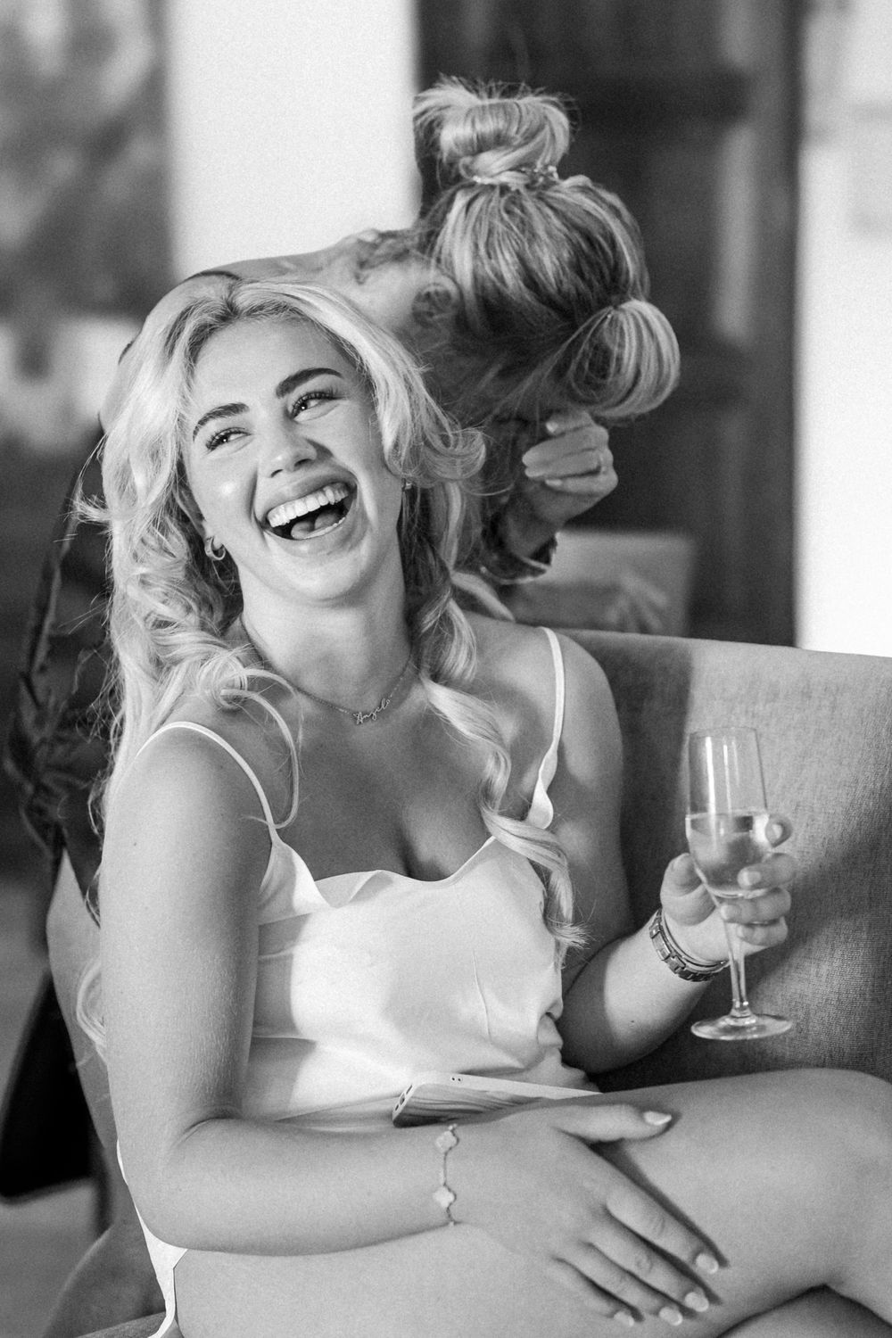 A black and white candid photo of a joyful moment during wedding preparations.