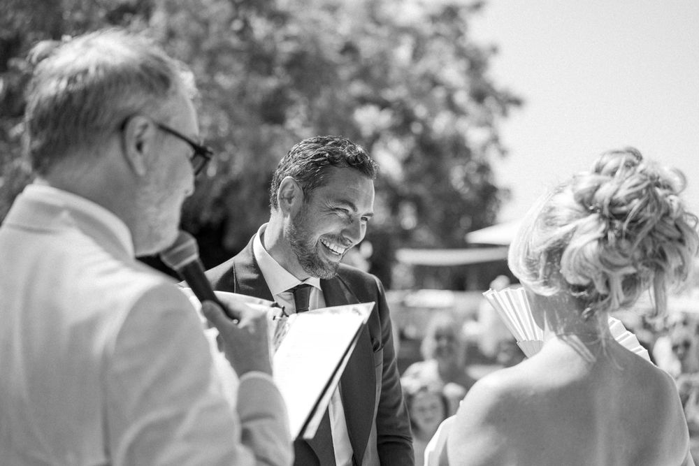 Black and white candid shot of joyful moment during outdoor wedding ceremony.