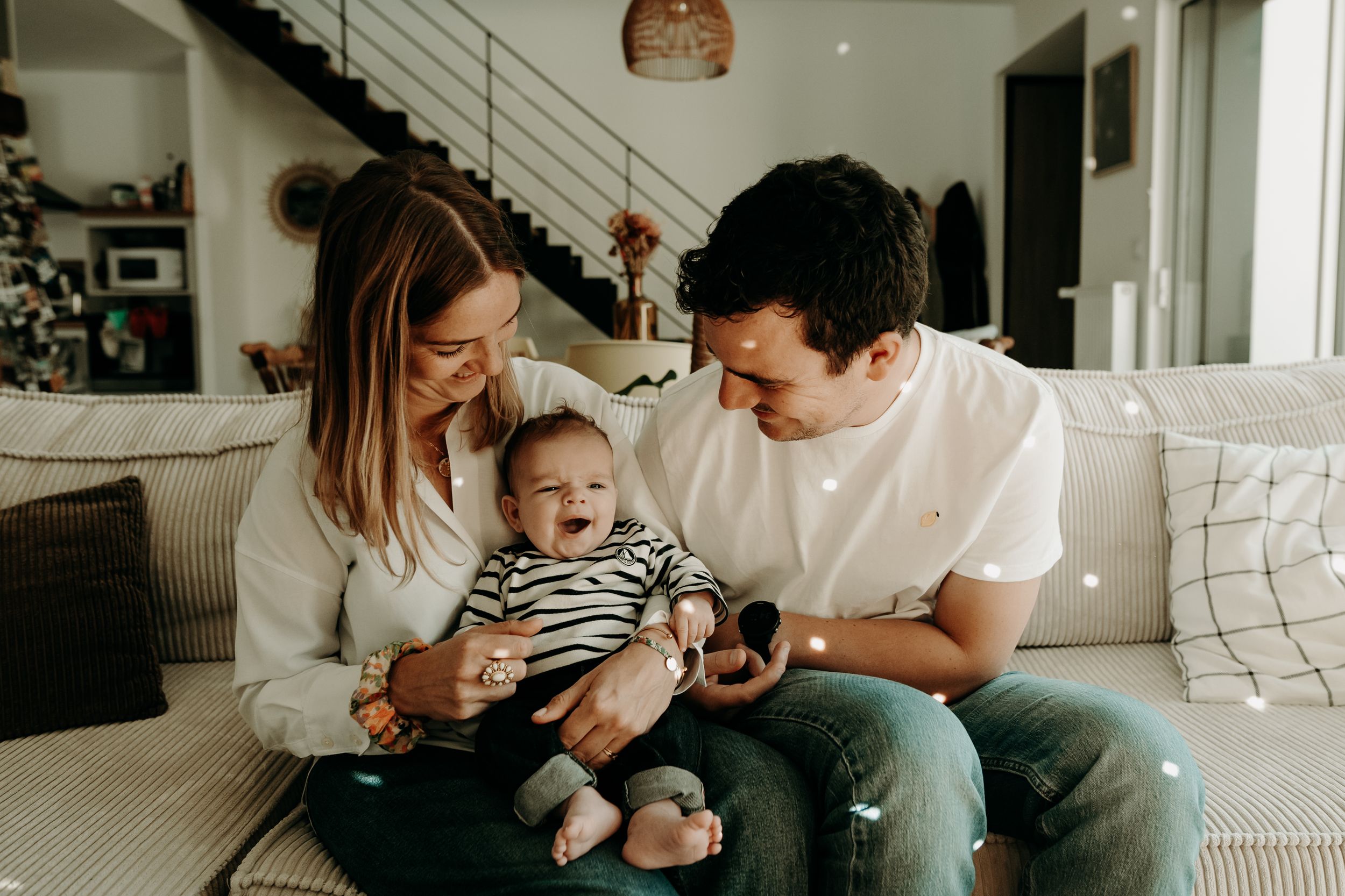 Family enjoying quality time together on a cozy white couch in a bright modern living room.