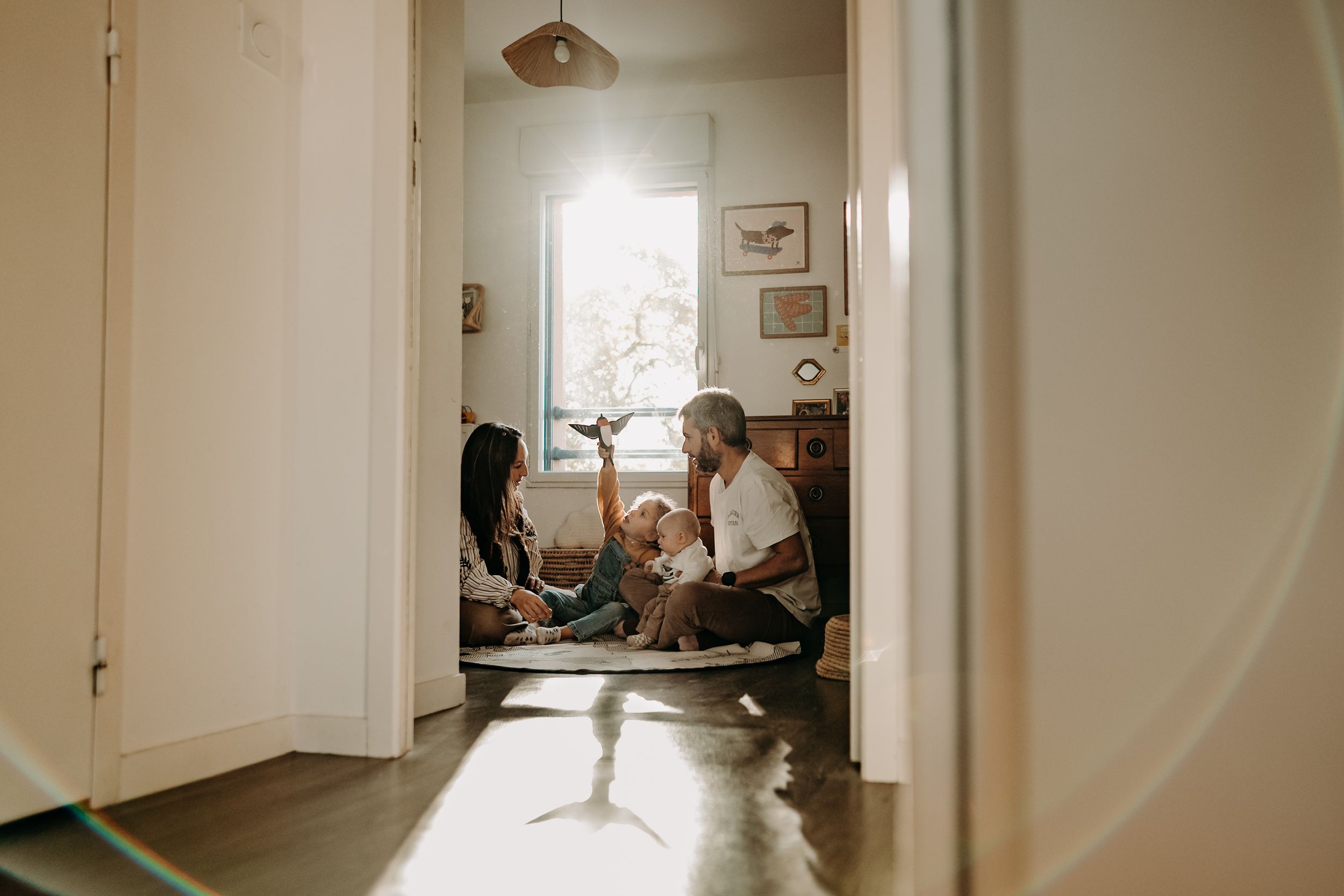 Sunlight streams through a window in a bright hallway, creating dramatic shadows and illuminating the white walls.