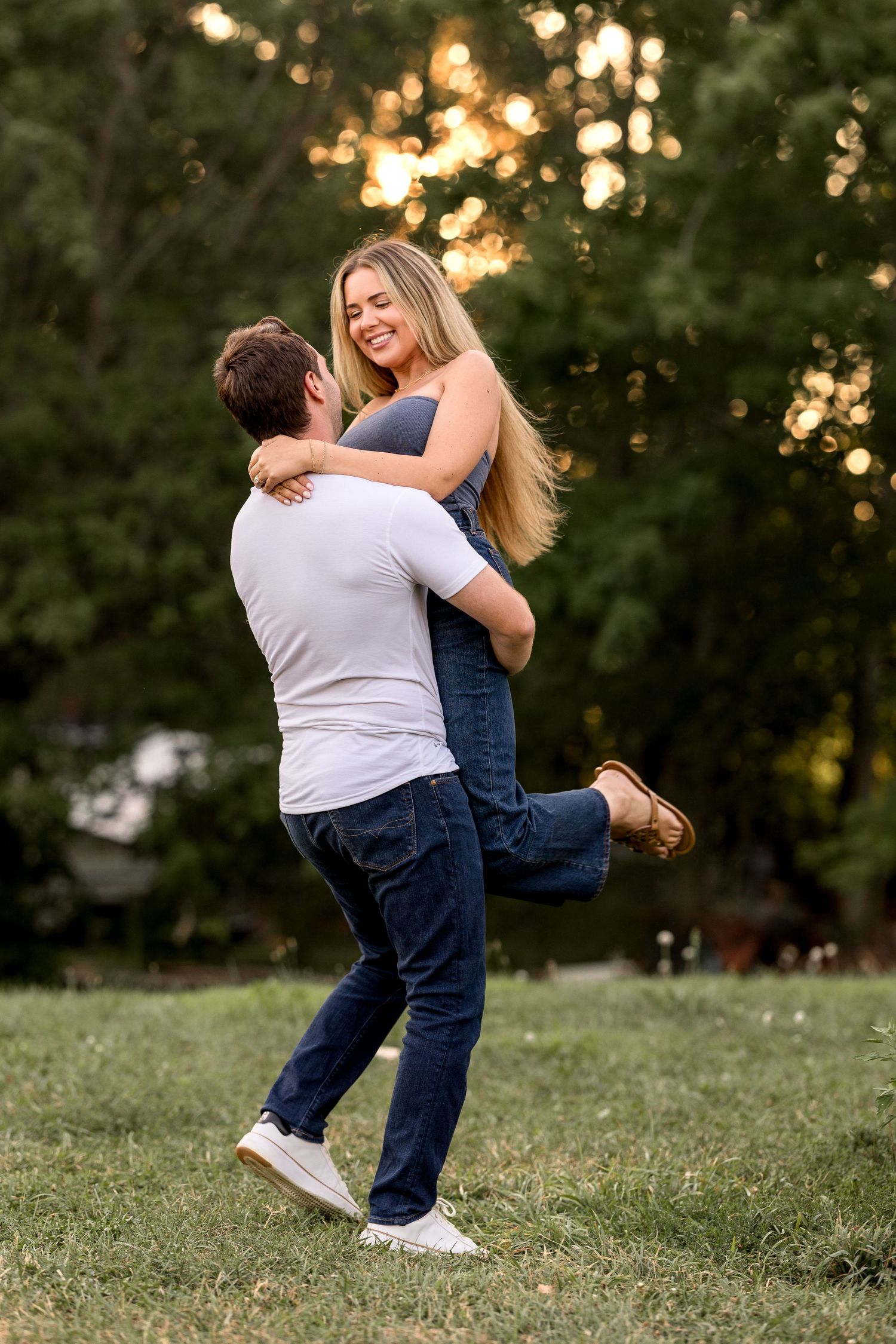People playing and embracing on grassy lawn during sunset.