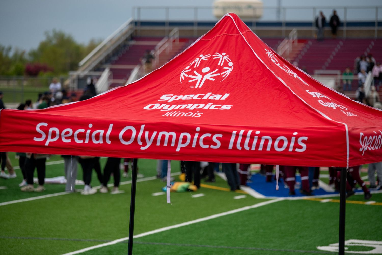 Row of red Special Olympics Illinois tents set up at an outdoor sporting event.