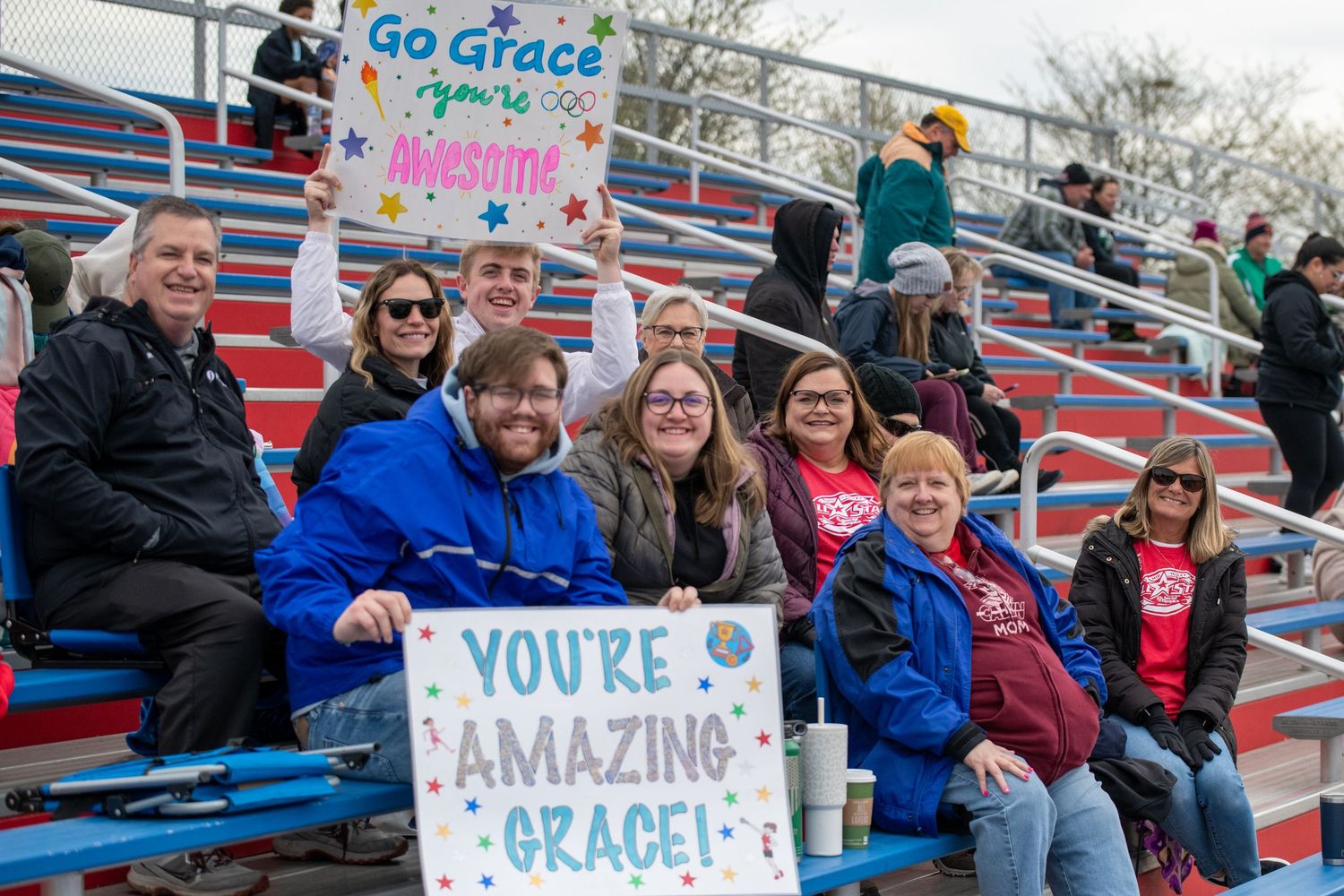Colorful handmade support signs displayed in stadium bleachers at sporting event.