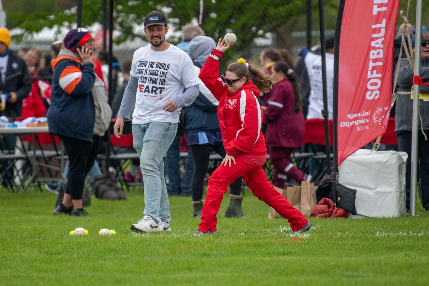 Athletes in red and gray uniforms participating in Special Olympics activities on grass field.