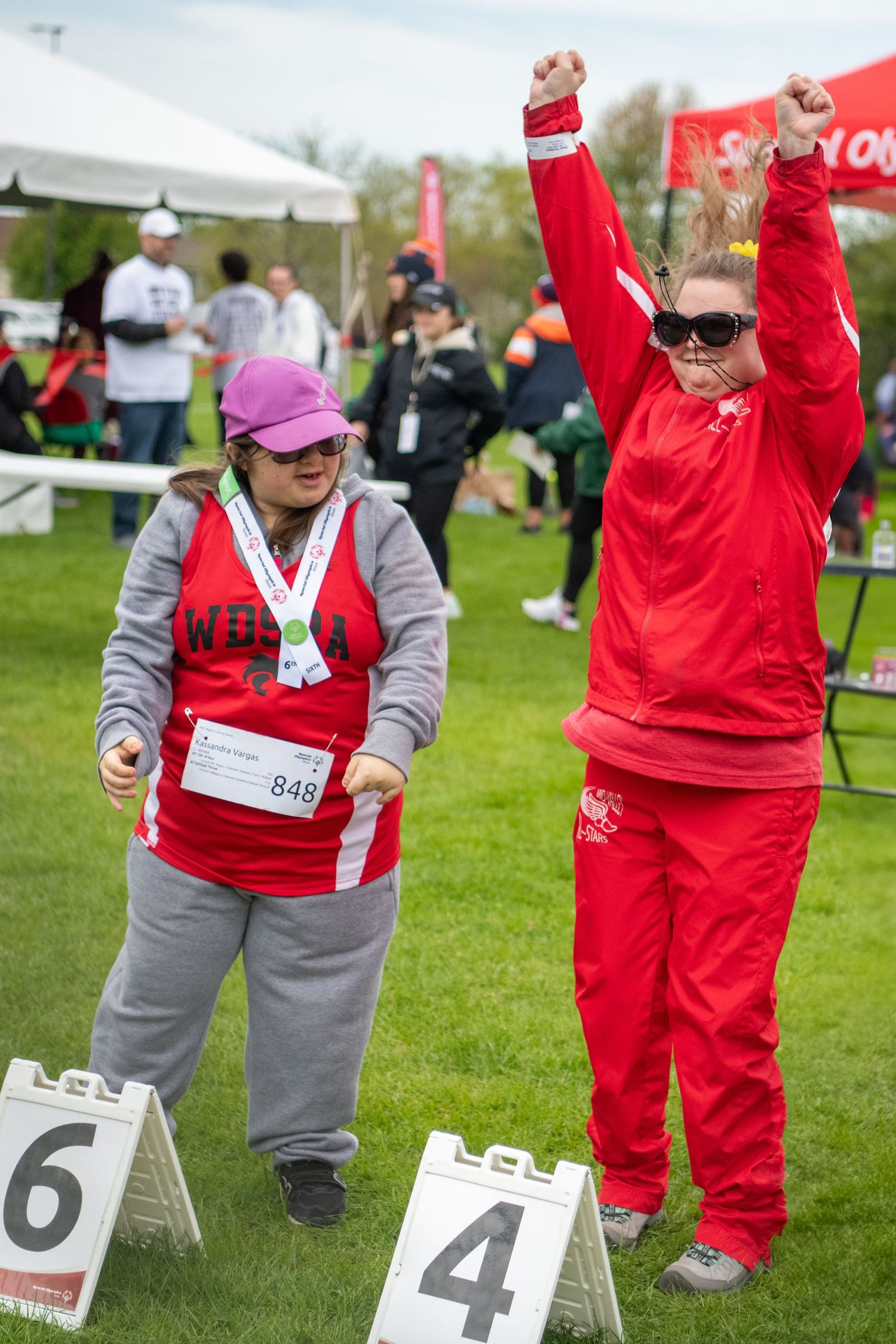 Special Olympics participants competing in numbered lane positions on grass field.