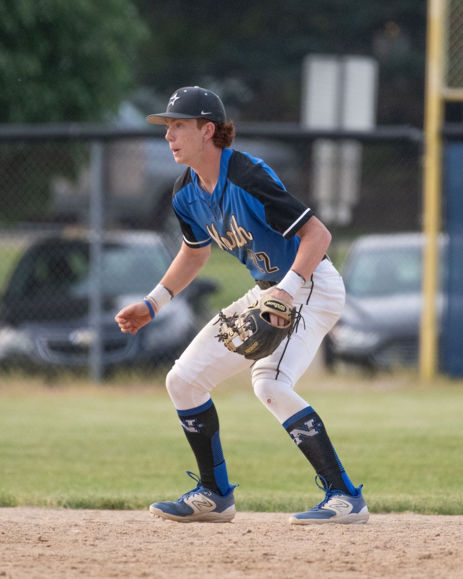 Baseball player in blue uniform takes defensive stance on infield during game.