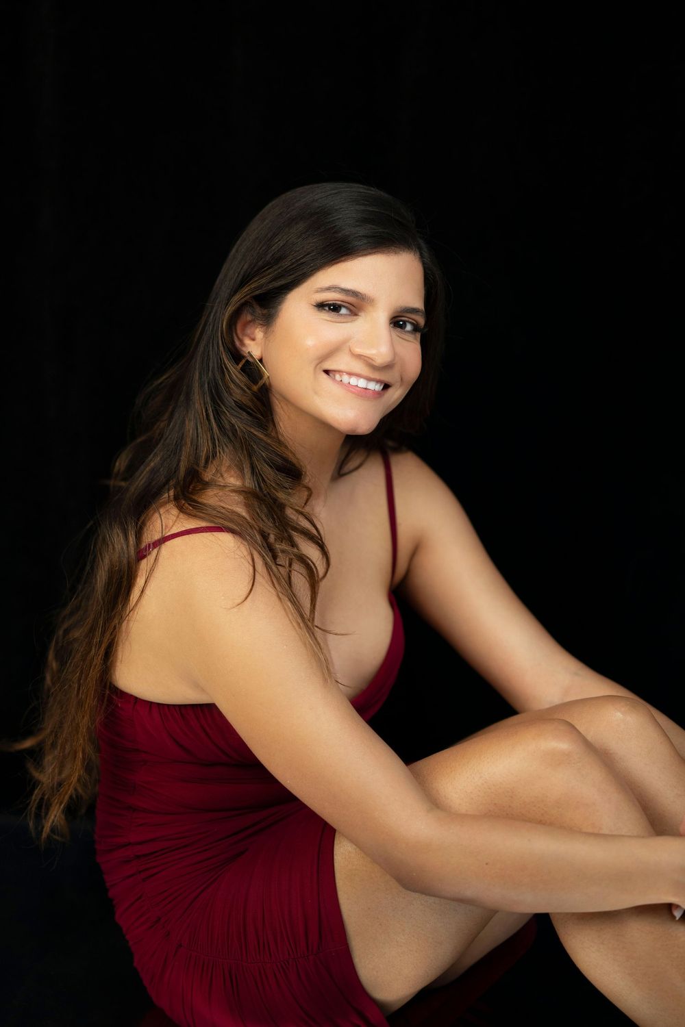 Casual seated portrait in red dress with natural lighting.