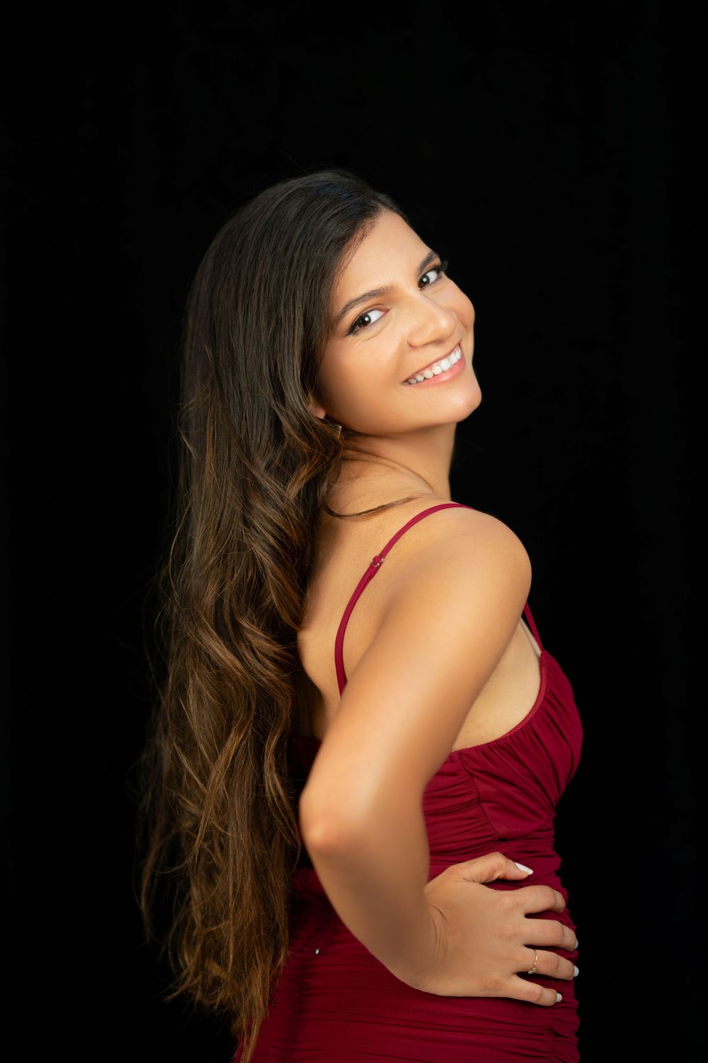 Studio fashion shot with burgundy dress against black backdrop.