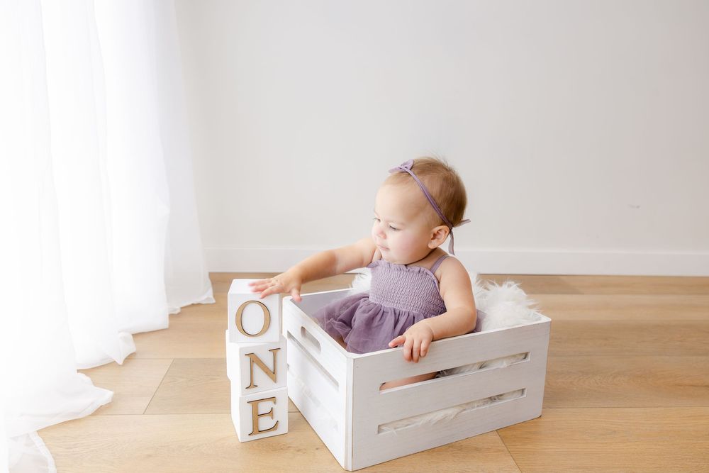 Baby in white wooden box prop with letter blocks for professional newborn photography session.