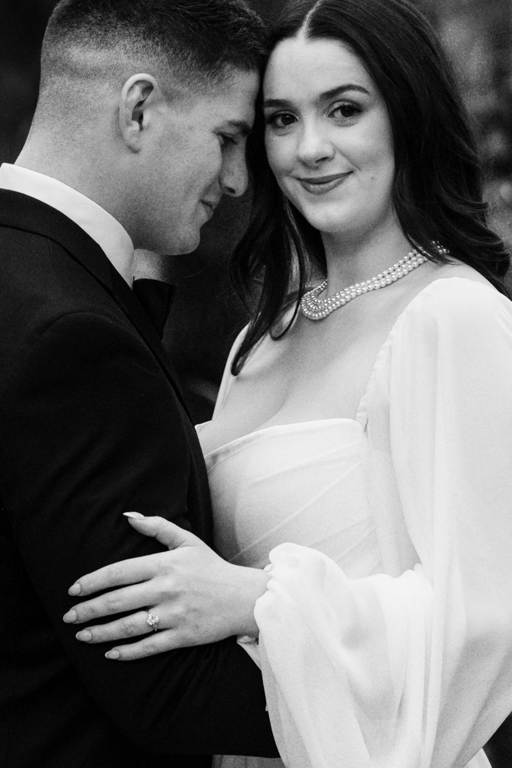 A romantic black and white wedding photo series showing intimate moments between a bride in white and groom in dark attire.