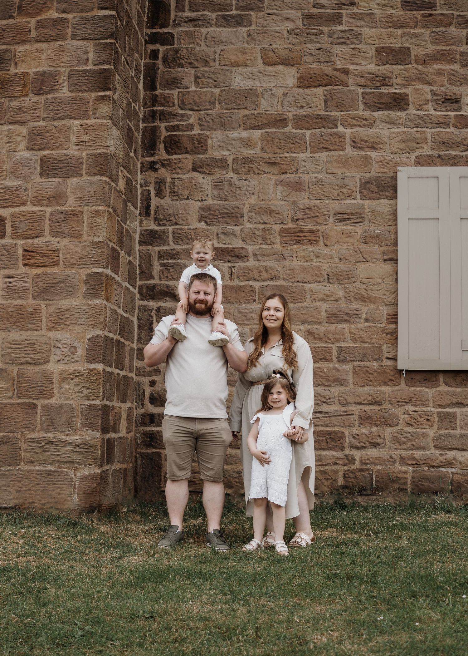 Family Photoshoot - A family group poses together against a rustic stone wall background.