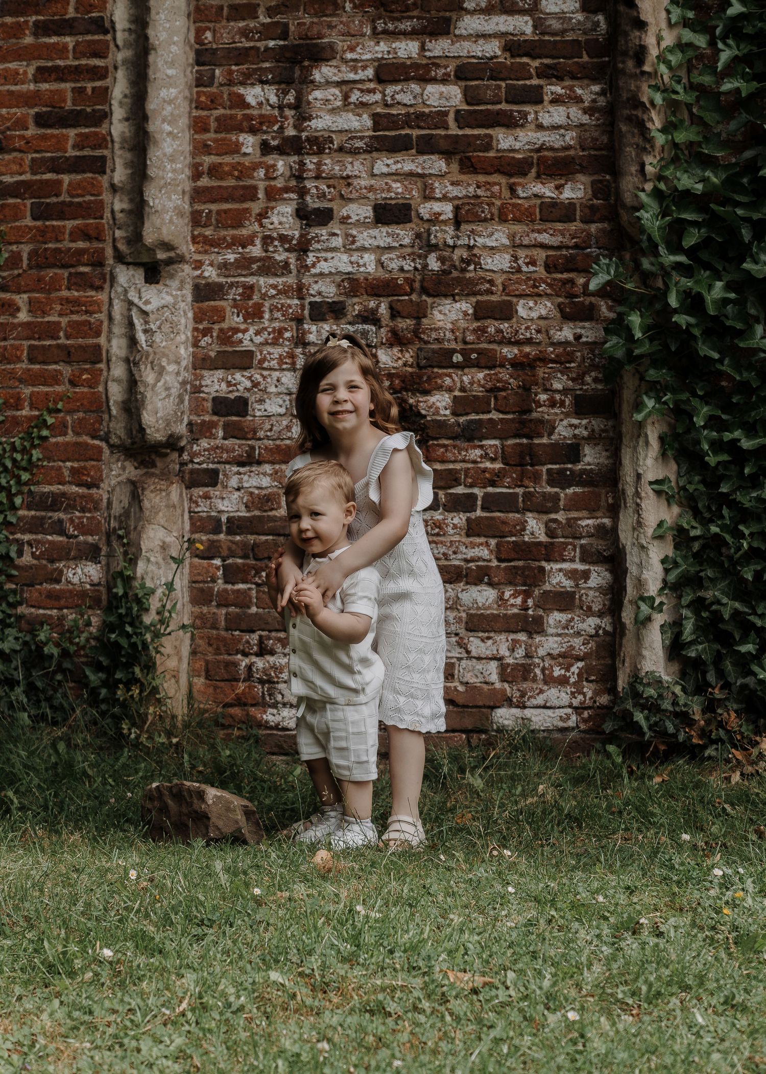 Family Photoshoot - Children play and laugh together in front of an ivy-covered brick wall.